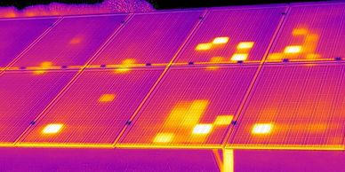 Thermal image of solar panels showing hotspots in bright yellow and orange.