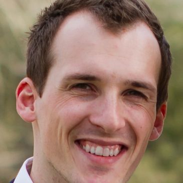 Close-up of a smiling young man outdoors.