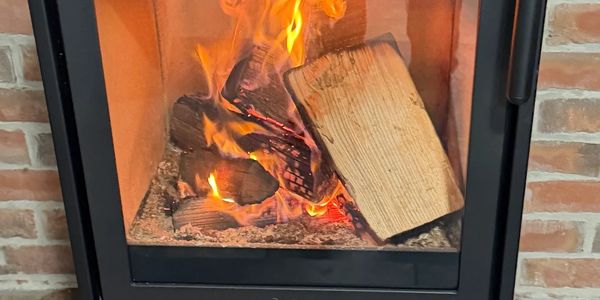 Contura Wood stove burning brightly inside a modern fireplace.