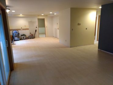 Empty room with light-colored flooring and some items in the corner.