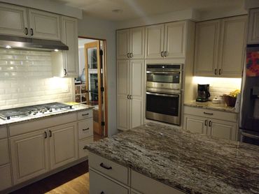 Modern kitchen with granite island and white cabinetry.