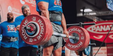 A muscular man deadlifting heavy weights at Arnold Expo.