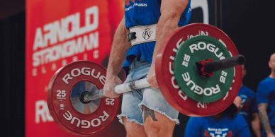 Bearded strongman lifting heavy barbell at Arnold Strongman Classic.