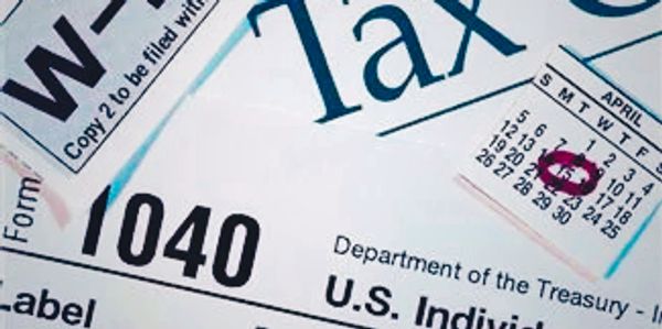 Close-up of U.S. tax forms including 1040 and W-2 with April 15 deadline marked.