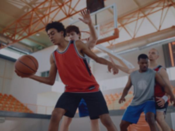 Young men playing basketball indoors in a competitive game.