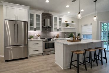 Modern kitchen with white cabinetry, stainless steel appliances, and island seating.
