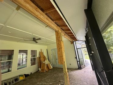Porch under construction with exposed beams and building materials.
