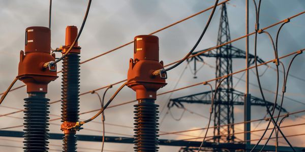 Close-up of electrical insulators and power lines against a sunset sky.