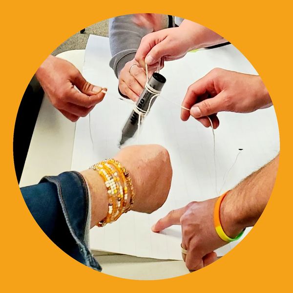 Hands holding a marker with strings attached. Team Builiding