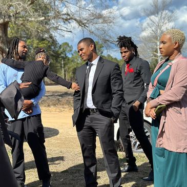 A group of well-dressed people outdoors, engaging in conversation and smiles.