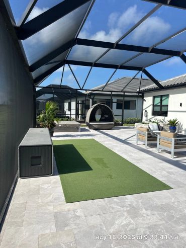 Modern outdoor patio with artificial grass and seating area.