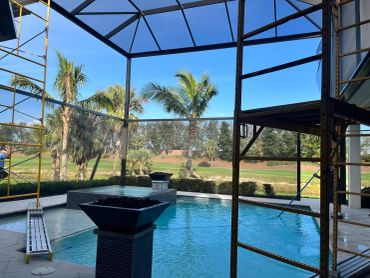 Pool area under construction with scaffolding and palm trees.