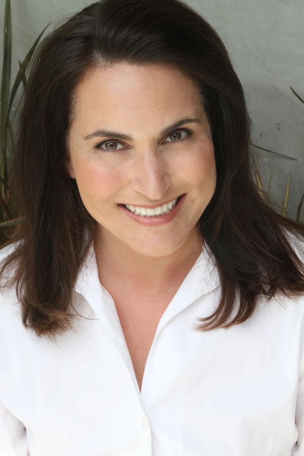 Smiling woman with dark hair wearing a white shirt.