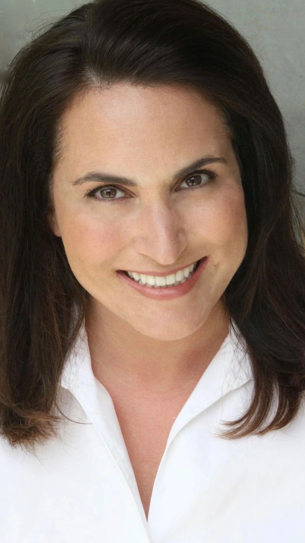 Smiling woman with dark hair wearing a white shirt.