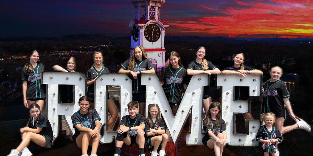 Youth baseball team posing with large RDME letters at sunset.