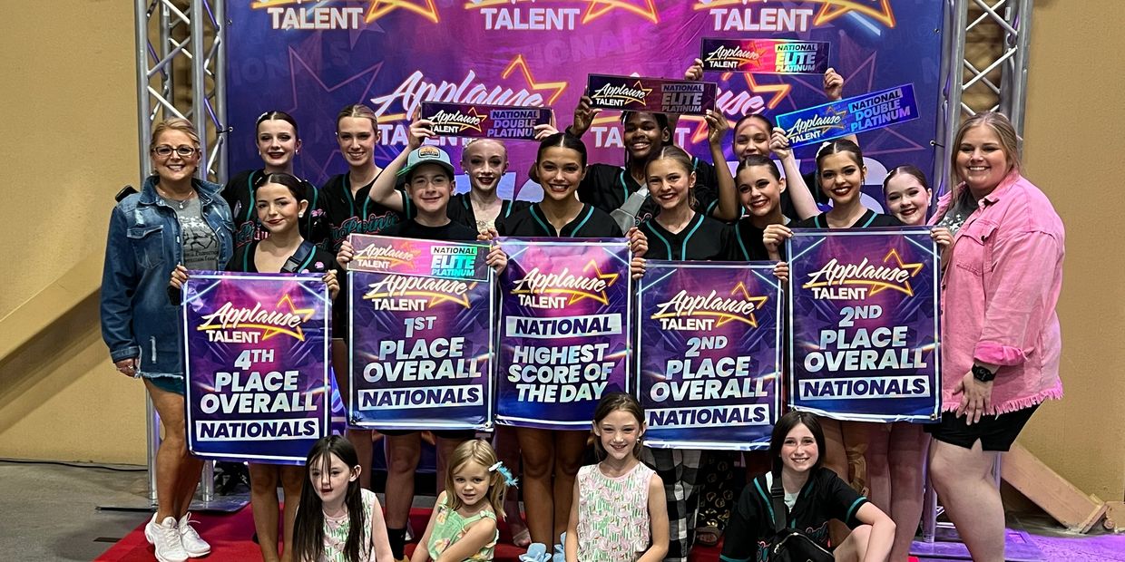 A dance team proudly holding banners for top placements at Applause Talent Nationals.