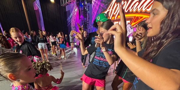 Children dancing and enjoying a lively event with colorful stage lighting.
