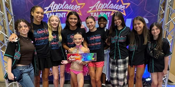 A group of young dancers posing with a National Double Platinum award at Applause Talent event.