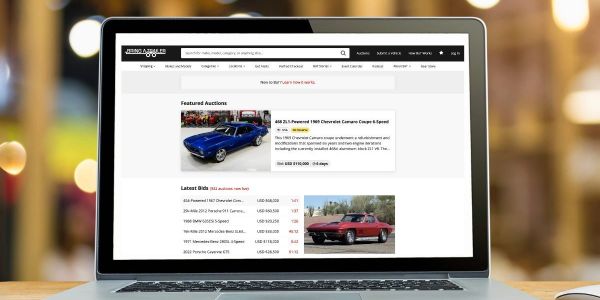 Laptop displaying an auction website for classic cars.