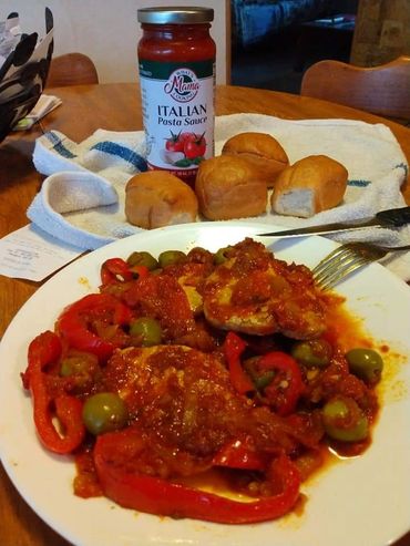 A dish with red bell pepper, pasta sauce, and olives