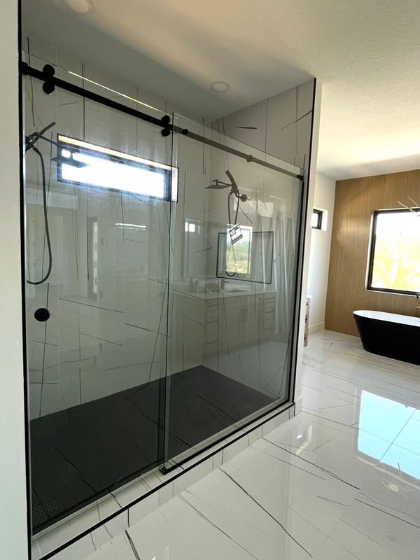 Modern bathroom with glass shower and black bathtub.