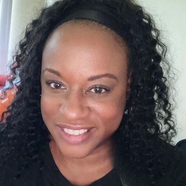Smiling woman with curly hair and a black headband.