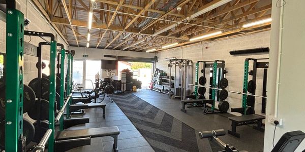 Spacious gym with various weightlifting, functional equipment and cardio machines.
