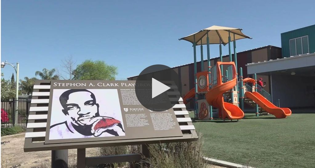 Stephon A. Clark Playground with orange slides and a commemorative sign on a sunny day.