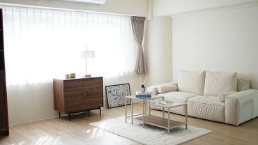 Bright minimalist living room with a beige sofa and wooden dresser.