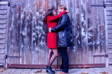 Couple embracing affectionately in front of a rustic wooden door.