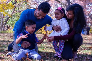 A family enjoying autumn leaves together in a park.