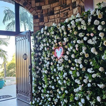 Flower wall backdrop with pink neon heart

