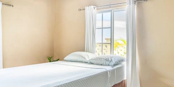 A bed room with a white bed and wooden frame