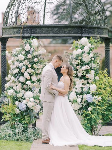 Bride and groom sharing a romantic moment under floral gazebo.