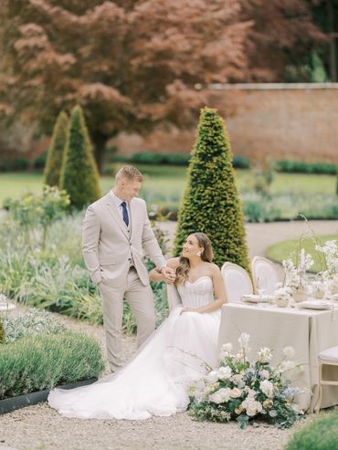 Bride and groom share a tender moment in a garden setting.