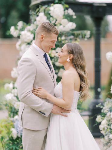 Bride and groom smiling at each other during an outdoor wedding.