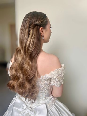 Elegant bride with long wavy hair and lace off-shoulder wedding dress.