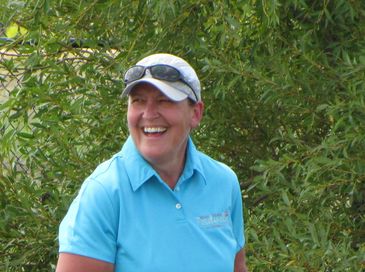 Dale Ward smiling, wearing a blue polo shirt standing in front of outdoor greenery,