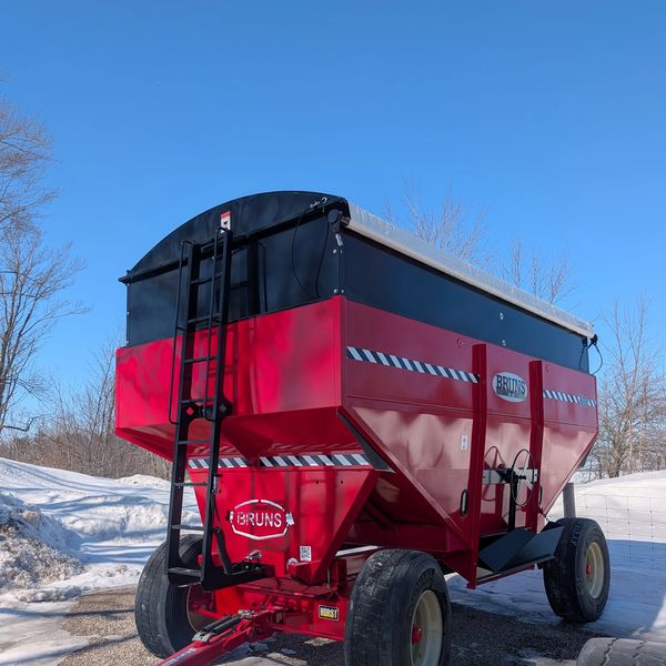 Red Bruns grain cart with large wheels on a snowy day.