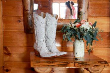 Detail shot of boots and flowers with bride reflection in mirror