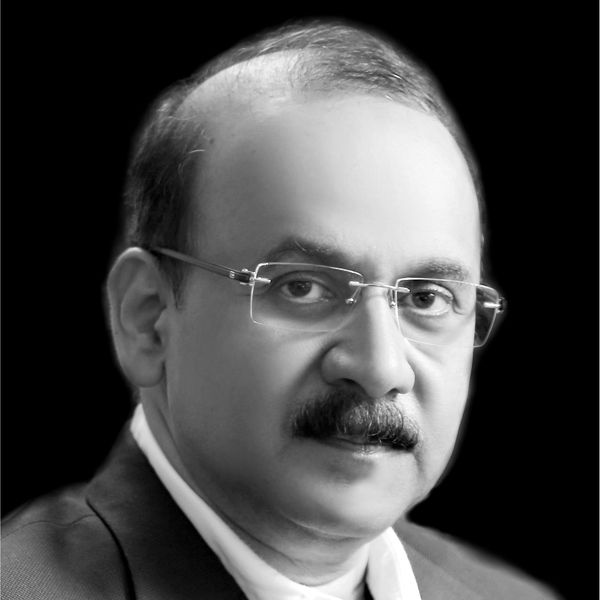 Portrait of a middle-aged man with glasses and a mustache against a black background.