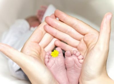 Fertility coaching baby's feet in mother's hands