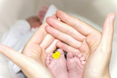 Fertility coaching baby's feet in mother's hands