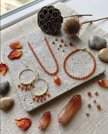 Orange gemstone jewelry set with necklace, bracelet, and earrings on a textured stone slab.