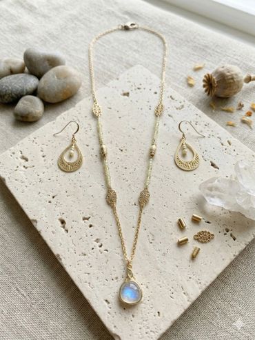 Elegant gold jewelry set with a teardrop pendant and matching earrings.