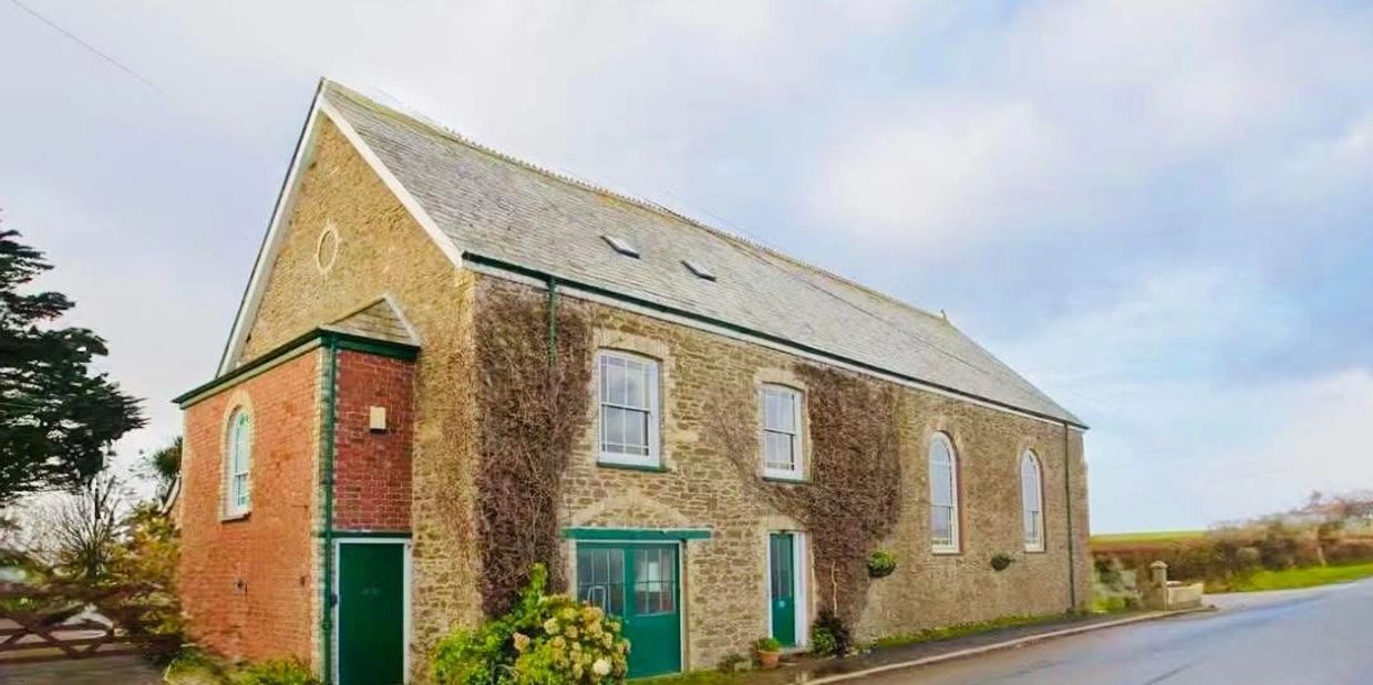 Stone house with green accents and a steep roof.