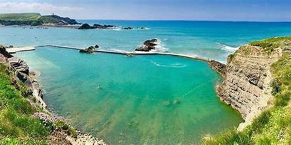 Natural sea pool with clear blue water and coastline.