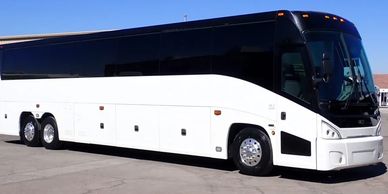 A large white tour bus parked on a sunny day.