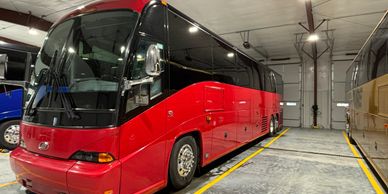 A sleek red coach bus parked indoors.