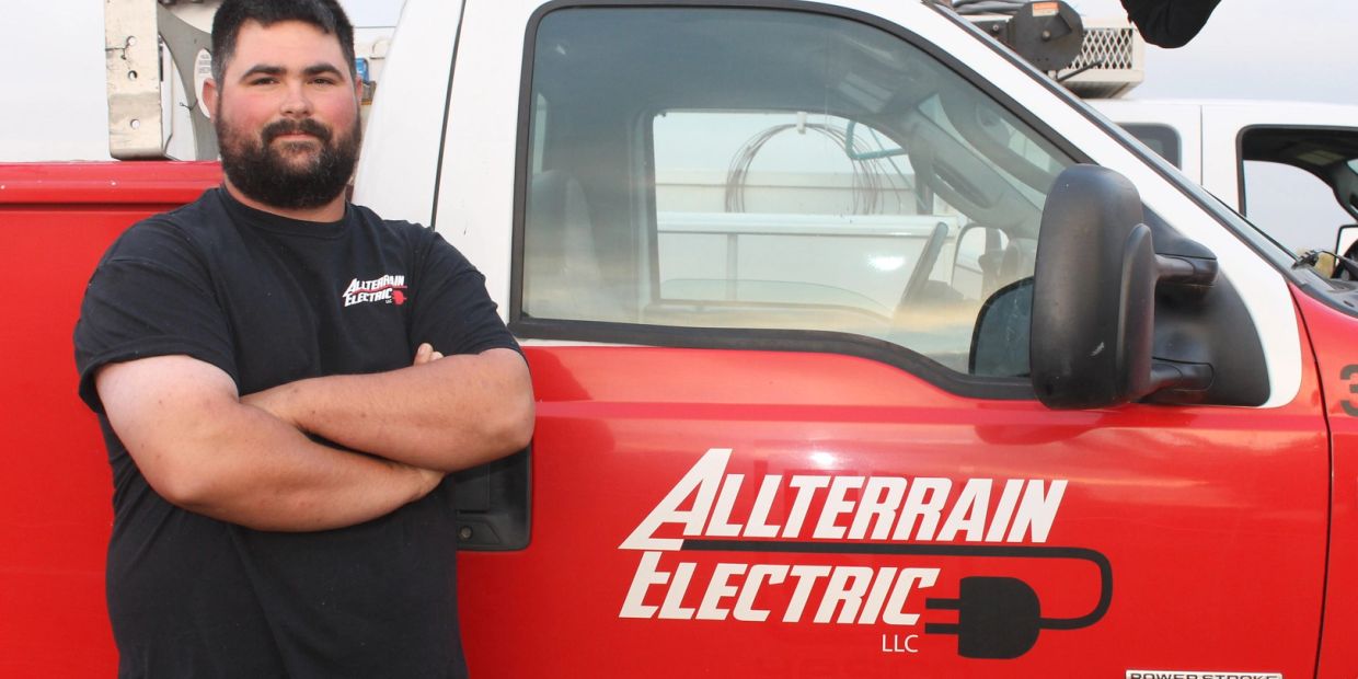 Man standing with arms crossed by Allterrain Electric vehicle.